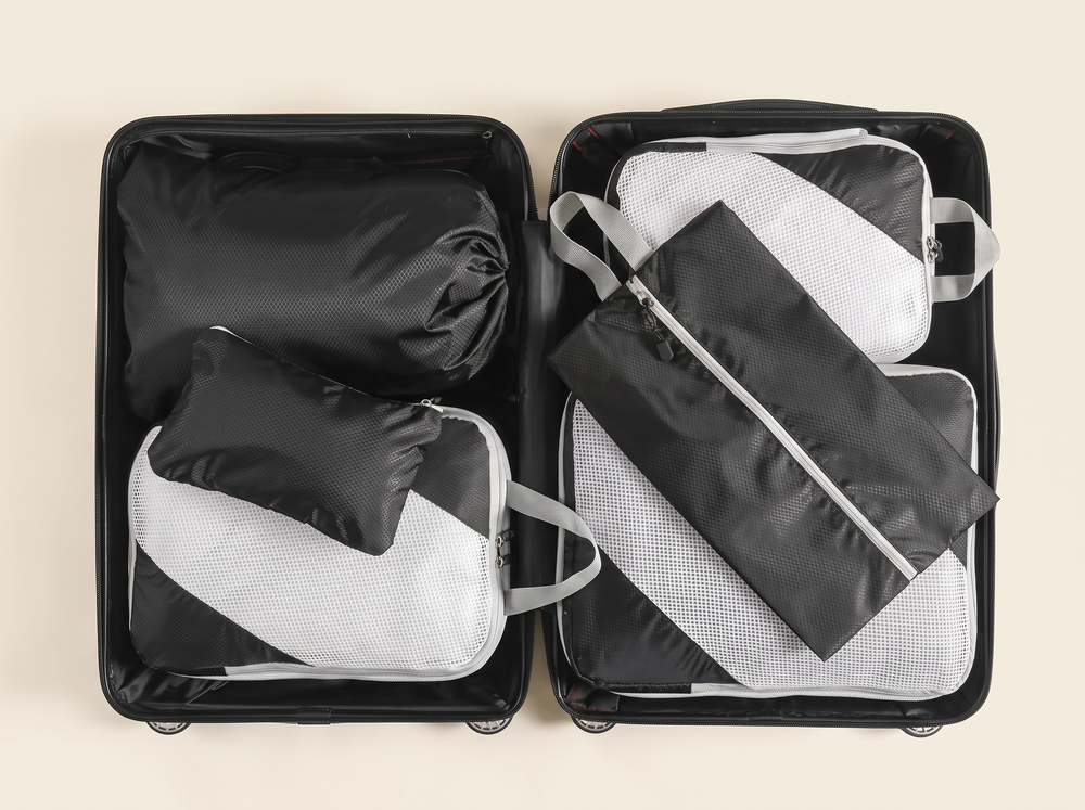 AI-generated illustration of black travel organizers arranged inside an open suitcase.