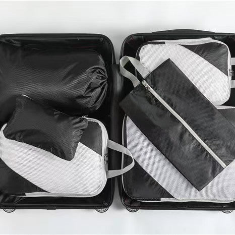 Black six-piece packing organizer set arranged inside an open suitcase; suitcase not included.